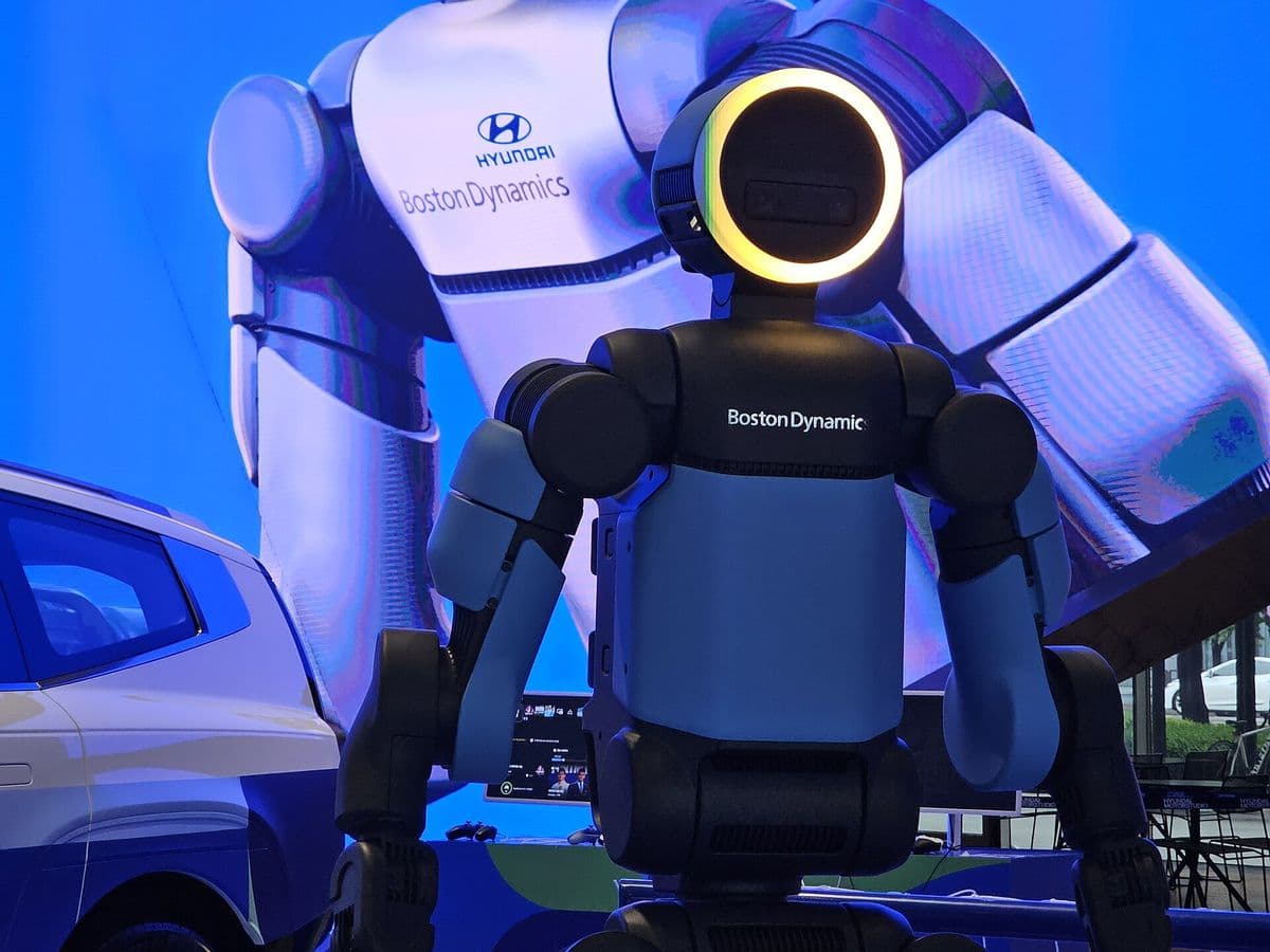 Boston Dynamics’ electric Atlas humanoid robot, seen from behind, in front of a large Hyundai display.